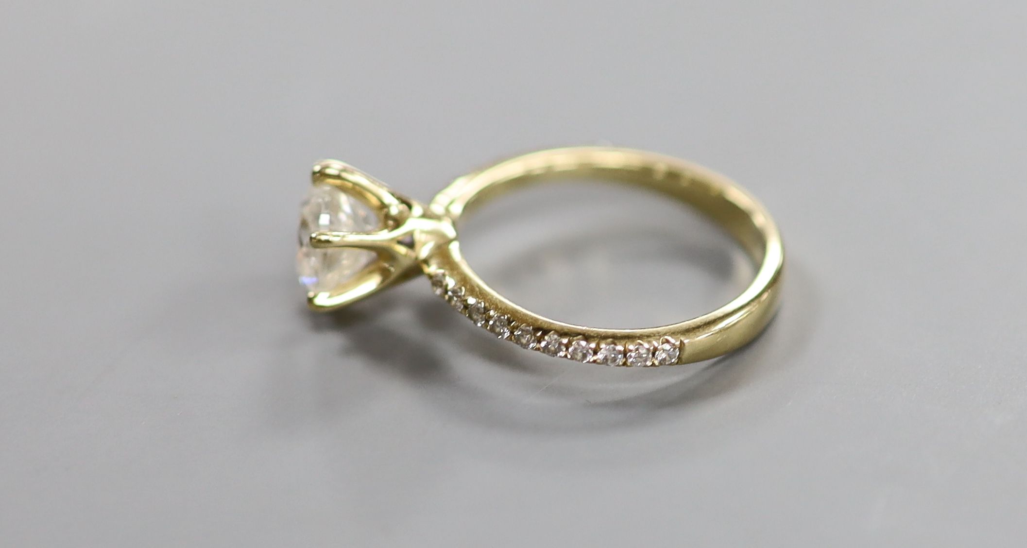 A modern 14kt yellow metal and single stone diamond ring, with diamond chip set shoulders